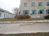 Здание Аптеки ОАО Фармация по ул. Первомайской,54. Цоколь  разрушен,окна здания не окрашены,  на клумбе сухие растения