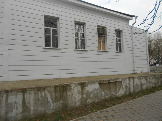 Здание Ростелекома по ул. Первомайской, 24. Плитка на цоколе разрушена, окна забиты фанерой.